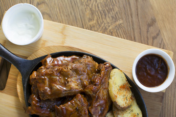 Delicious barbecued ribs seasoned with a spicy basting sauce and served with chopped potato on a...