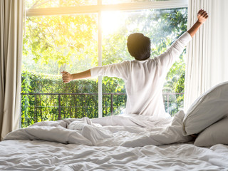 lazy man happy waking up in the bed rising hands to window in the morning with fresh feeling relax