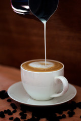 Coffee in a white cup and coffee beans on the floor.