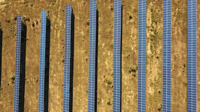 Aerial View. Flying over the solar power plant with sun. Solar panels and sun. Aerial drone shot. 4K 30fps ProRes (HQ).