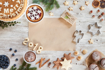 Christmass composition with snowflakes, sweets, candies, cinnamon, number year 2018 on a beige wooden background. Branches of furry spruce, dried orange, hazelnuts. Top view. Copy space.