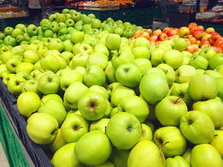 Many fruits green apples lying in boxes in supermarket