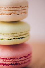 Blurred colorful French macarons. Beige, green, pink macaroons in a column. Nice bokeh background. Delicious French cakes and pastries. Macro food photo for design, menu, cafe, restaurant, web, sites.