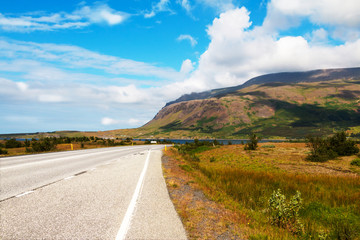 Beautiful icelandic deserted roadway along ocean fiord and green hills. Copy space.