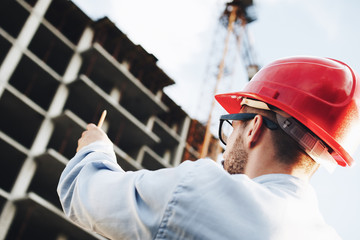 Young businessman directs the construction of skyscraper. Architect inspects construction site
