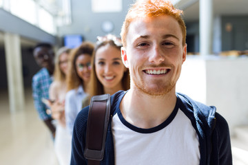 Group of happy young students looking at camera in a university.