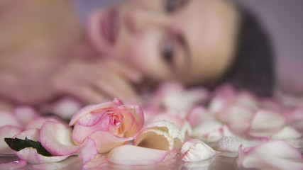 Obraz na płótnie Canvas Fresh Rose petals and pink rosebud. Blurred Woman face with clean Healthy skin on background