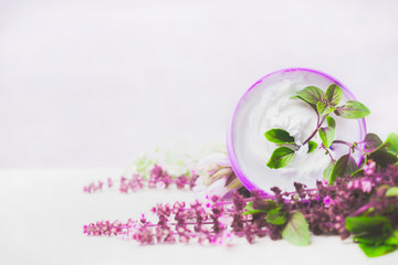Obraz na płótnie Canvas Skin care cream in jar with purple herbs on white wooden background. Natural cosmetic concept