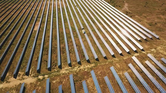 Aerial View. Flying over the solar power plant with sun. Solar panels and sun. Aerial drone shot. 4K 30fps ProRes (HQ).