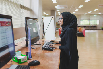 Arabic woman typing on computer , searching data in the library.