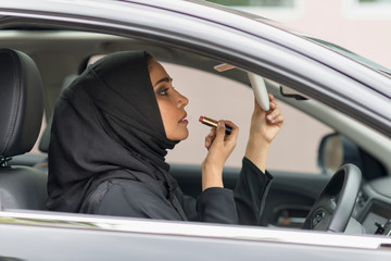 Arab women using make-up inside car.