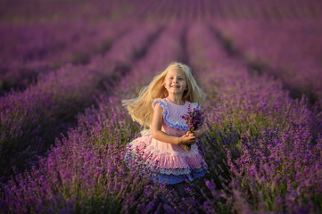 Fototapeta na wymiar Beautiful girl in a field of lavender on sunset. Beautiful girl in amazing dress walk on the field of lavender.