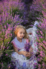 Beautiful girl in a field of lavender on sunset. Beautiful girl in amazing dress walk on the field of lavender.