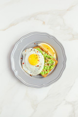 Toast with egg and avocado on a marble table. Top view. Idea for breakfast