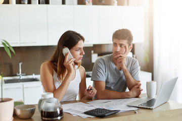 Busy businesswoman preparing financial report while being at home, calling her business partner...