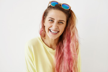 Headshot of attractive young female with pink hair tips, wearing yellow casual clothes, having...