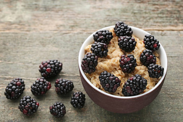 Oatmeal in bowl with blackberries on wooden table