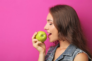 Portrait of young woman with apple on pink background