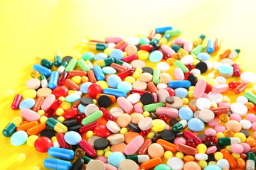 Different colorful pills on yellow background