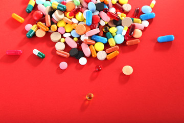 Different colorful pills on red background