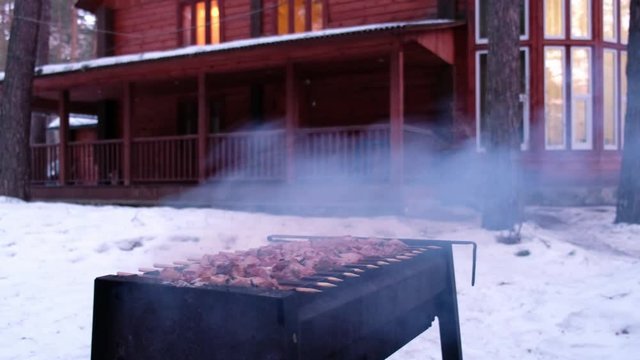 Panoramic video of meat shashlik on iron brasier barbecue with cottage on background