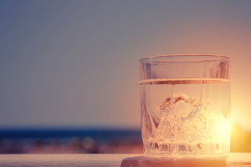 Glass of water on the background of beautiful sunset. Selective focus.