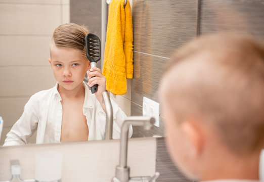 Little Boy Brushing His Hair With A Comb In The Bathroom