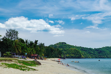 Fototapeta na wymiar Summer vacation on the Pantai Tengah Beach, Langkawi, Malaysia. Unidentified tourists relax on paradise beach, sunbathe and swim