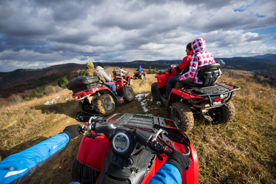 View from ATV a group of people riding a quad bikes on a mountain road under a sky with clouds in autumn