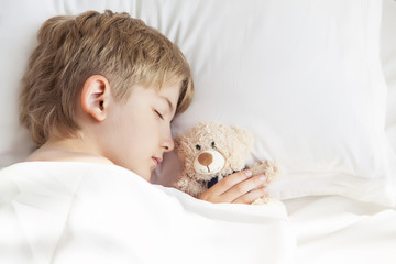 The boy is sleeping with a teddy bear