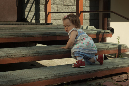 11 months adorable caucasian baby girl development, climbing up stairs at the street