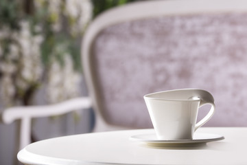 White cup and saucer. On a white table.