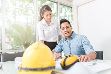 Engineer and architect discussing about new construction project at table with equipment in office
