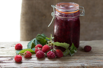 Homemade jam with raspberry on the wooden table.