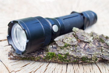 pocket LED flashlight lies on a tree bark