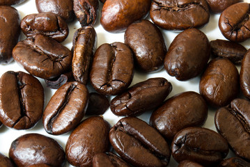 Macro shot of coffee beans on top of a white surface
