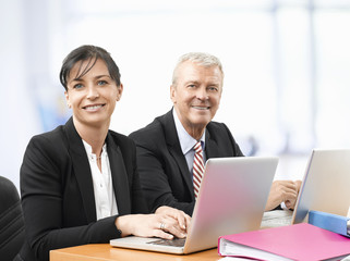Obraz premium Business team at work. Shot of an senior investment advisor businessman and his female financial assistant analyzing financial data while working on laptops. 