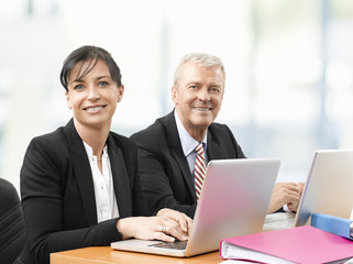 Business team at work. Shot of an senior investment advisor businessman and his female financial assistant analyzing financial data while working on laptops. 