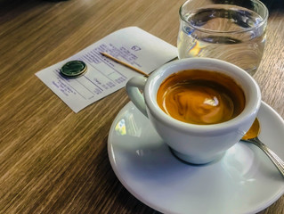 Espresso coffee on the table with bill and mug.