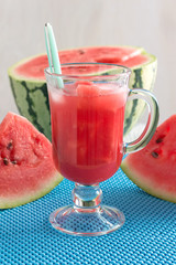 Fresh watermelon juice with chunks of watermelon on a blue napkin.