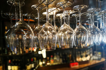 Empty wine glasses hanging on rack in bar
