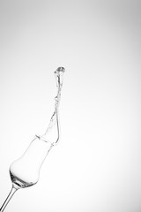 Grappa schwappt aus einem Glas in die Höhe im Hochformat