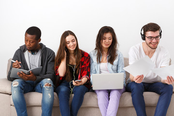 Young diverse people listen to music with gadgets