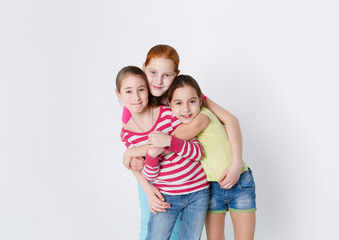 Portrait of three smiling girls at white studio background