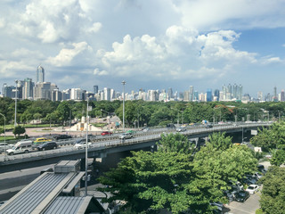 Cityscape showing green natural park and forest with diversity background of city with high buildings and road / highway with traffic