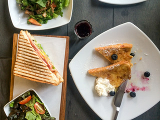 Top view of breakfast / brunch meal with french toast with blueberry, vegetable salad, and bacon egg sandwich on table for concept of healthy eating / breakfast or brunch meal on Sunday in restaurant