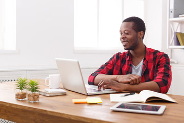Happy black businessman in casual office, work with laptop