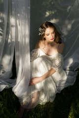 Fototapeta na wymiar the beautiful girl in a wedding dress on a grass