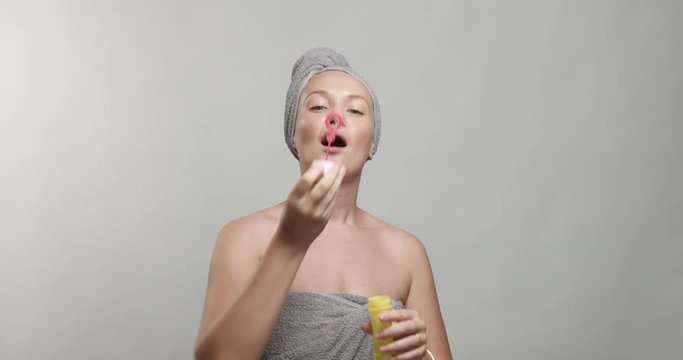 30's woman wears a towel after bath surrounded by soap bubbles