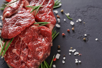 Rib eye steak and spices on wood at black background